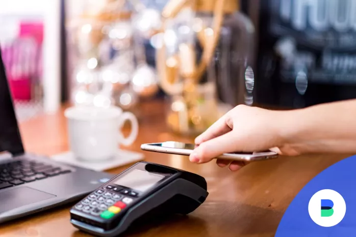 Férfi a mobiltelefonja érintésével fizet a bankszámlájáról a boltban